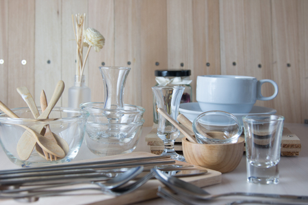 Set of kitchen ware on table, Kitchen Utensils. Glass bowl, Wooden bowl, spoon, fork, knife, cup of coffee, bottle, chopsticks, chopping block.の写真素材