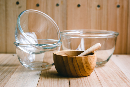 Glass bowl and Wooden bowl, spoon, fork, knife put on the wooden table set of kitchen ware.  Kitchen Utensilsの写真素材