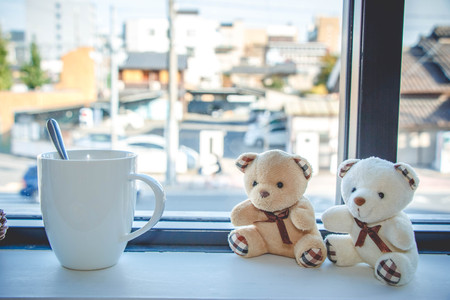 Coffee cup and Lovely couple bear sit on wooden bar near window. Morning sunshine at Kyoto cafe, Japan.の写真素材