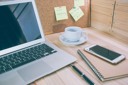 digital laptop put near cup of coffee, office stationery, pen and smart phone put on notebook, modern office concept.の写真素材