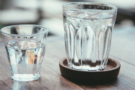 Glass of water on a wooden table. Water drops on glass, fresh and pure water.