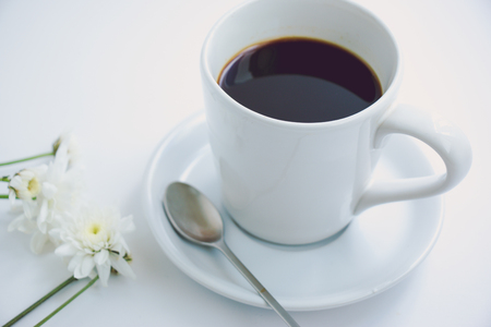 White cup of hot black coffee with morning fresh croissant on white table. smoke and scented arabica coffee bean in fresh morningの写真素材