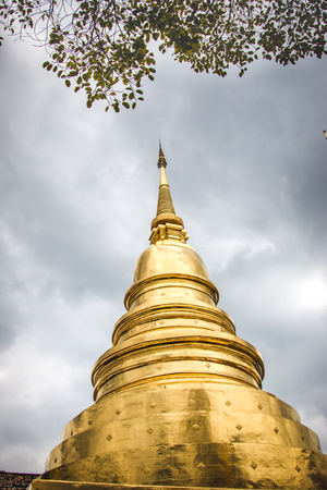 Golden pagoda at Phra Singh Temple, old city centre of Chiang Mai Strom is coming, blue dark and big cloud.の写真素材