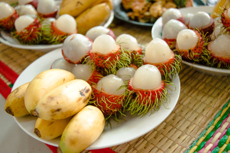 Set of fresh fruit Banana and Rambutan peeling on white dish, make offering to monkの写真素材