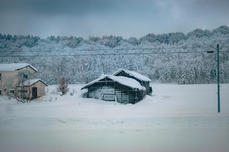 House and hut covered by snow. snow storm is coming in  Winter rural landscape.  Forest Trees in...