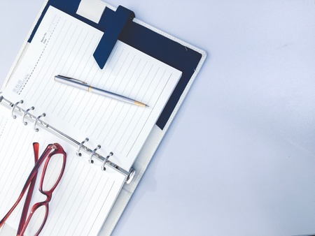 Pen on notebook and glasses on table in modern officeの素材