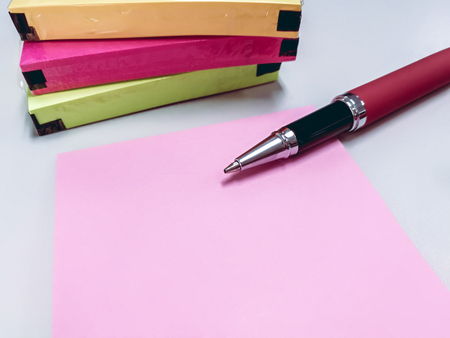 write note and item list in blank pink paper note. put near pen and pack of colorful papernoteの写真素材