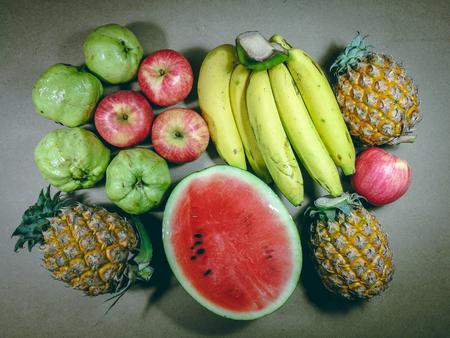 Pile of Banana, apple, papaya, pineapple, guava, watermelon fruits, Assortment of exotic fruits isolated on grey background. Creative layout made of fresh fruits. Flat lay. Banana, apple, papaya, pineapple, guava, watermelonの写真素材
