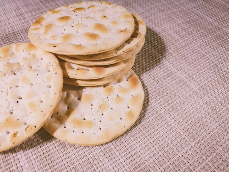 Dry thin crackers on a sackcloth. Old wooden background. Tasty crispy crackers cookies idea for...