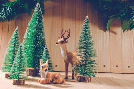 Reindeer in Christmas tree forest the ornament wooden background. Merry christmas and happy new year...