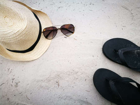 Hat and sun glasses with black sandal on sand beach, item and accessories for summer vacation and...