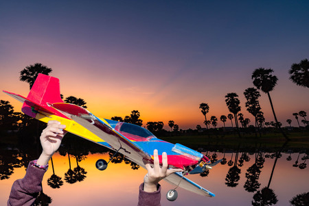 The hand holding the airplane. To the in the city