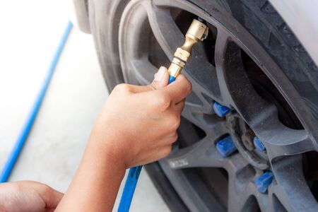 Woman's hands fill the car tire with a simple matter.の写真素材