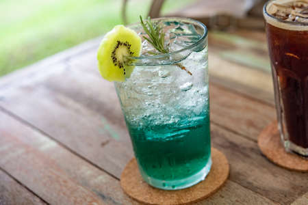 Delicious kiwi soda water sweet and fragrant in a glass of ice cold on the wood floor jpgの写真素材