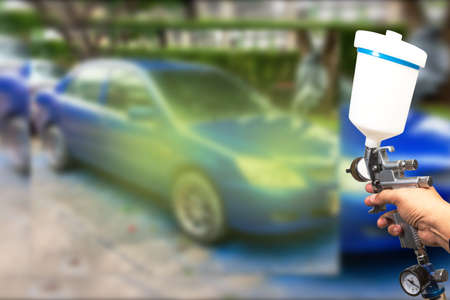 Blurred background paint sprayImage of the painter's arm hand holding industrial size spray gun used...