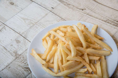 French Fries Asian street food in a white plate on the wooden floor French Fries, BBQ Sauce, Tomato...