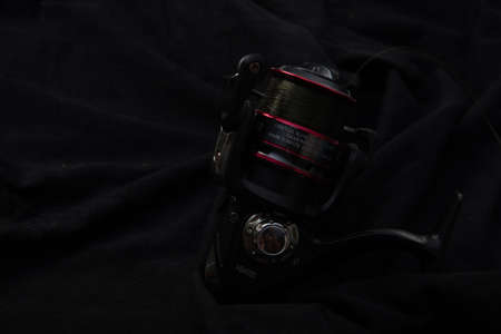 Fishing reel Fishing equipment on wooden wall background, indoors technology system