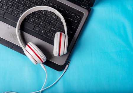 White red music headphones on technology background Notbook computer on a blue background. Happy...