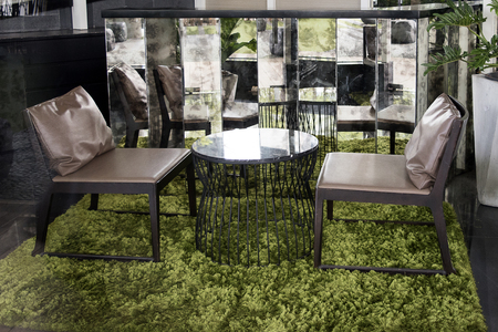 Modern furniture having brown leather chair and marble table on green grass carpet at the coffee shopの写真素材