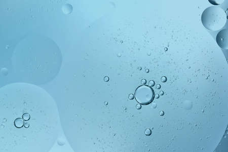 oil drop floating or Cosmetic liquid serum on the water blue bubbles backgroundの写真素材