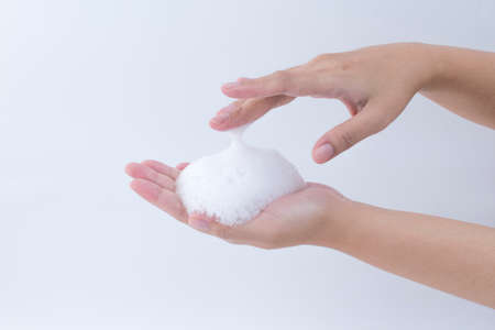 white soapy foam bubbles texture on hand. cleaning and wash essence facial cleanser skin care conceptの写真素材