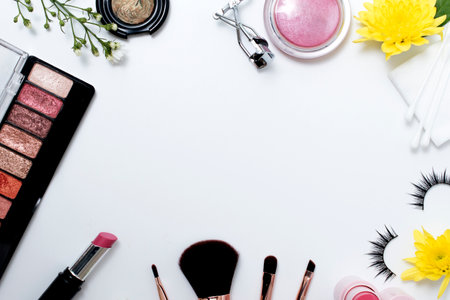 flat lay of decorative cosmetics with makeup brushes flowers and skincare products frame on white backgroundの写真素材