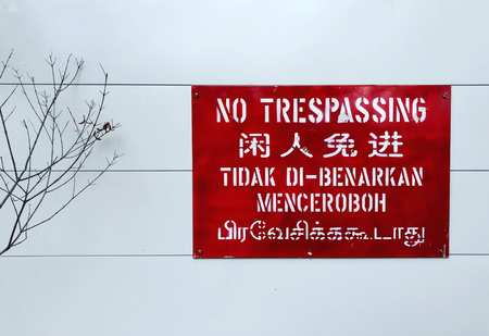 No trespassing sign in 4 different languages on a white wallの写真素材