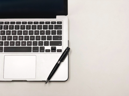 Top view of a laptop with a pen on working table.の写真素材