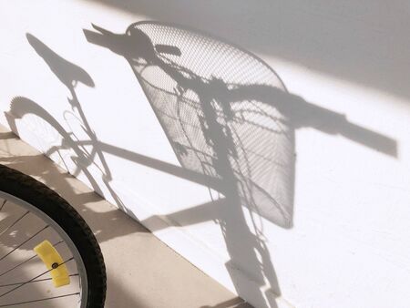 Shadow of bicycle with basket casted on the white wallの写真素材