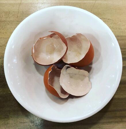 Eggshell in a bowl on wooden surface