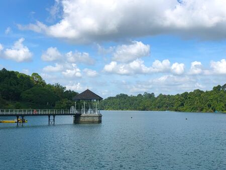 Distant view of sheltered bandstand in the middle of the lake under cloudy skyの写真素材