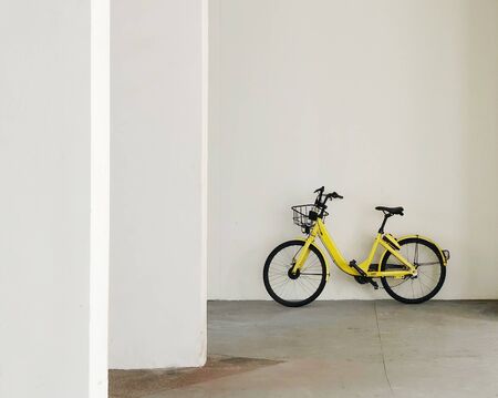 Yellow bicycle parked against the wallの写真素材
