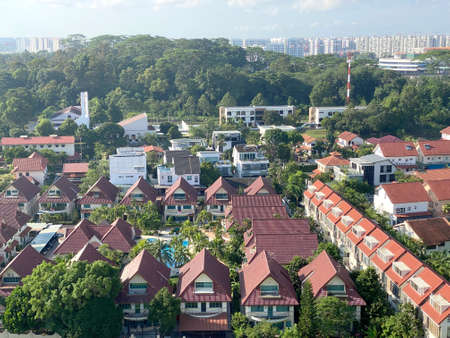 Aerial view of landed properties, bungalows surrounded by greenery, with residential apartments at the far backgroundの写真素材