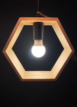 Light bulb with hexagon wooden frame isolated on a black backgroundの写真素材