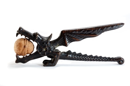 Old dragon shaped  nutcracker with nut on white background
