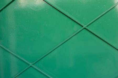 A close-up of a green iron wall with geometric pattern.