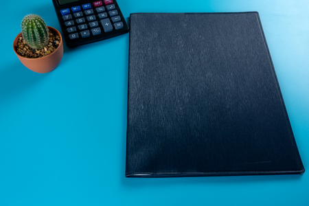 Empty business notebook calculator and Cactus cover on blue color background
