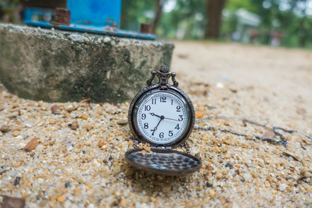 Vintage pocket watch on the sand on the playground.