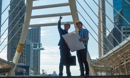 Young businessman with young engineers looking at a project on the construction site.の写真素材