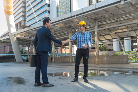 Businessmen shake hands with a young engineer in the city.の写真素材