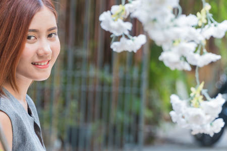 Beautiful young Asian woman face with a white flower on the right side of the image blurred. Copyspaceの写真素材