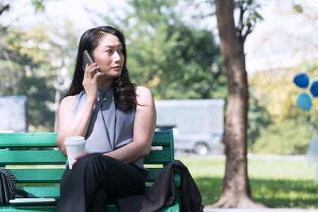 Concept relaxes time. Attractive business woman talking on smartphone with cup coffee sitting on...