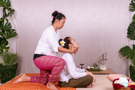 Concept thai Massage. Beautiful Asian young woman getting herbal massage thai massage in spa salon.Thai girl reflexology on shoulder with masseur.の写真素材