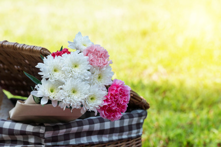Flowers in picnic basket on the green grass nature background with sunlight.の写真素材