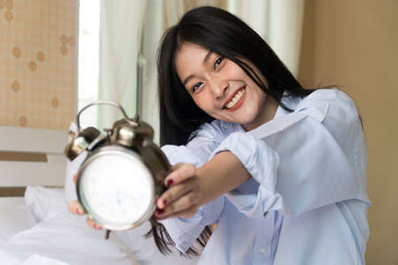 Top view happy smiling girl using smart phone for selfie on the bed. Beautiful young woman self-portrait with mobile camera lying on white bed. Concept lifestyle technologyの写真素材