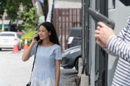 Beautiful woman talking phone and didn't know anyone holding gun secretly.Robbery, burglary with a...