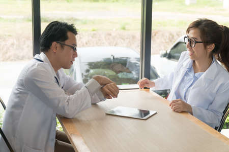 Coffee break two doctors meeting and talking in cafÃ©. Man doctor looking at his watch in coffee...