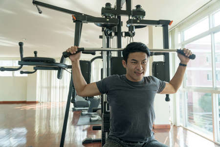 Handsome man playing with fitness machine in gym. Bodybuilder man doing heavy weight exercise with...