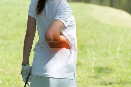 Back view of young woman touching her lower back muscles by painful injury, over nature background....