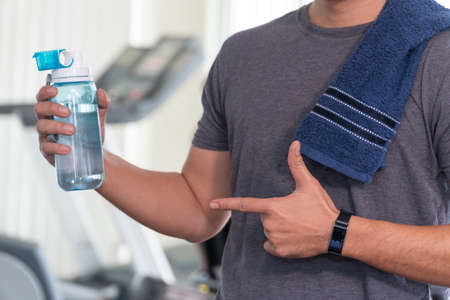 Close up young man athletes pointing to bottle of water in his hand. Concept exercise and healthy.